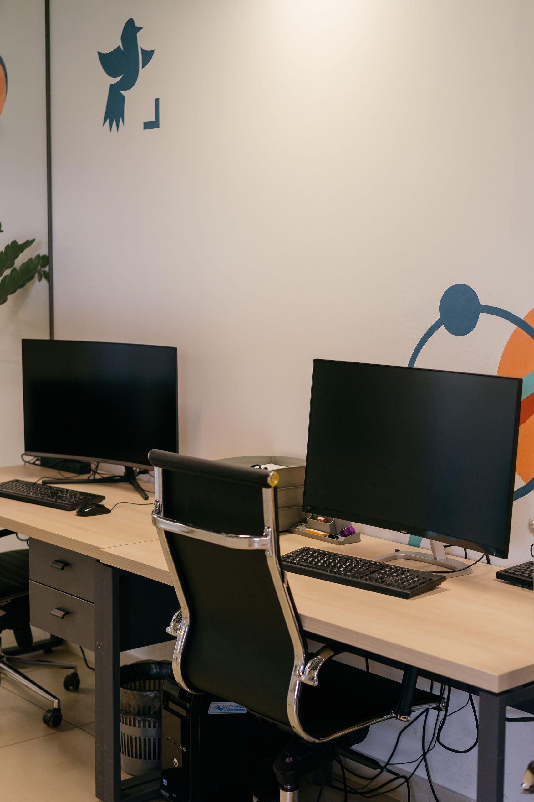 Empty modern office space with two desks, monitors, and stylish chairs.